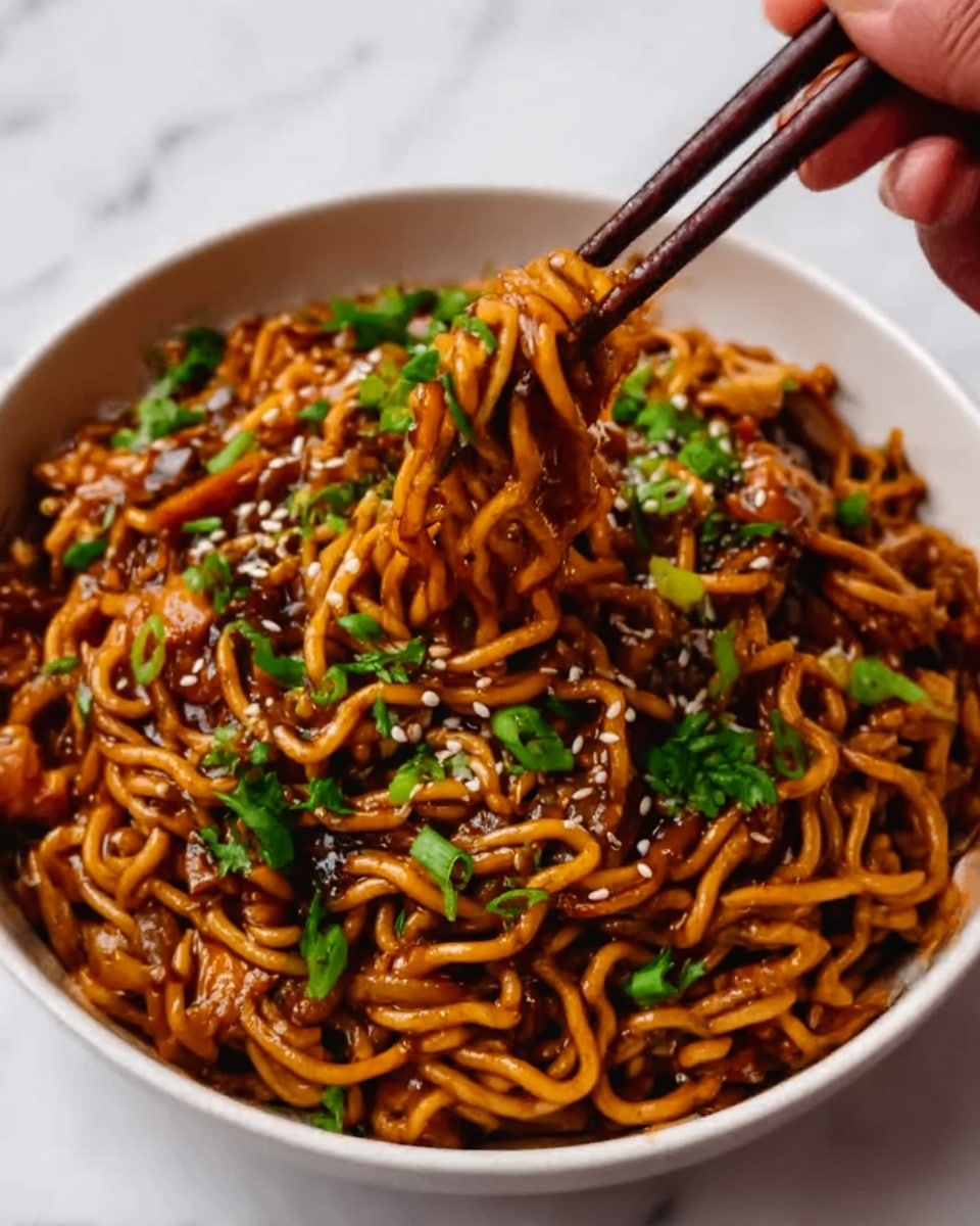 A white bowl filled with thick, curly noodles coated in a dark brown sauce, creating a glossy texture. On top, there is a layer of bright green chopped herbs scattered evenly across the noodles with a sprinkling of white sesame seeds for extra detail. A woman's hand holding dark wooden chopsticks is picking up some noodles from the right side of the bowl. The background is a white marbled surface. Photo taken with an iphone --ar 4:5 --v 7