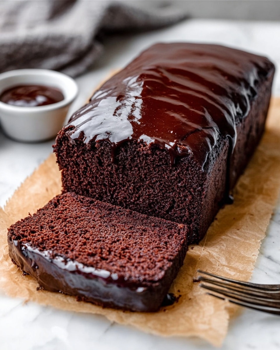 A chocolate loaf cake sits on a light-colored cutting board placed over a white marbled surface. The cake has a smooth, rich texture with a glossy chocolate glaze thickly spread on top, slightly dripping down the sides. One slice has been cut from the loaf and lies flat in front, showing a dense and moist dark brown interior. Near the cake, a small white bowl with chocolate sauce is partially visible, and a woman’s hand holds a knife poised to cut more. A black and white striped cloth is casually placed beside the board. Photo taken with an iphone --ar 4:5 --v 7
