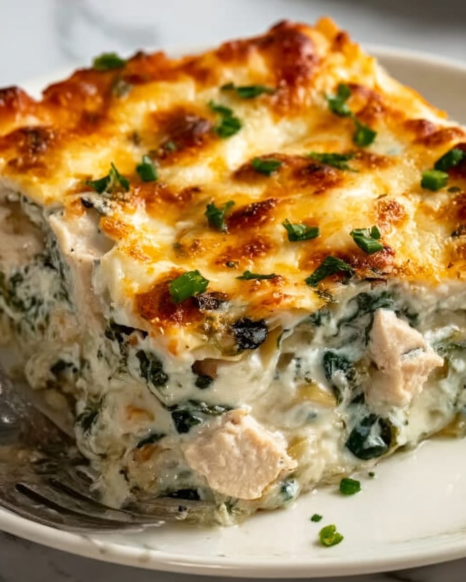 A close-up of a slice of lasagna showing three thick layers: the bottom layer is a creamy white sauce with specks of green spinach, the middle layer is white with chunks of chicken mixed with spinach, and the top layer is melted golden-brown cheese with small browned spots and bits of chopped green herbs scattered on top. The lasagna is on a white plate with a white marbled surface underneath, and a small part of a silver fork is visible at the bottom left corner. Photo taken with an iphone --ar 4:5 --v 7