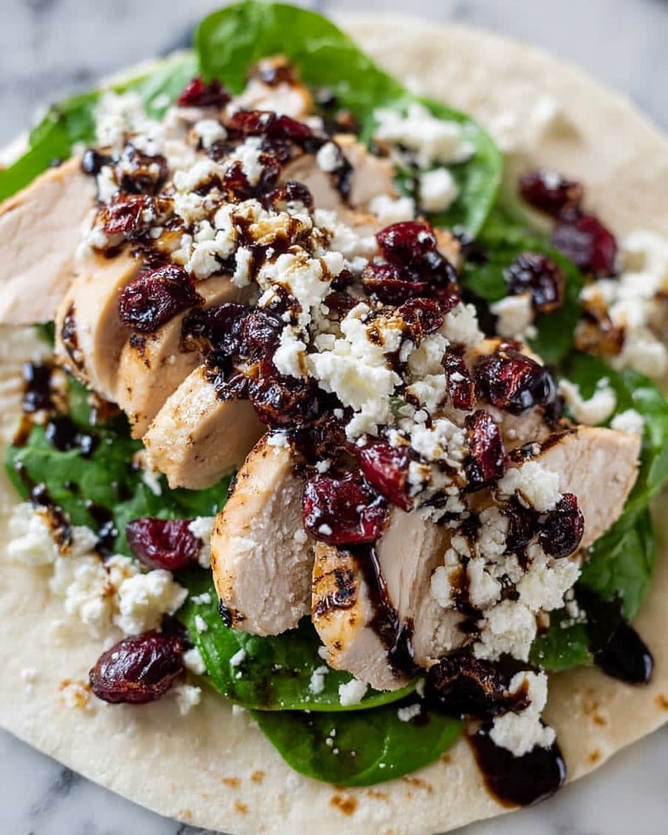 The dish shows several layers starting with a white tortilla base. On top of it is a layer of fresh, bright green leafy spinach. Next come slices of grilled chicken breast, lightly browned with grill marks, arranged in a row across the tortilla. Over the chicken, there is a generous sprinkle of small, white crumbly cheese. Scattered on top are deep red dried cranberries, adding a rich color contrast. The entire dish is drizzled with dark brown balsamic glaze, adding shine and texture over the top. The background is a white marbled surface. photo taken with an iphone --ar 4:5 --v 7