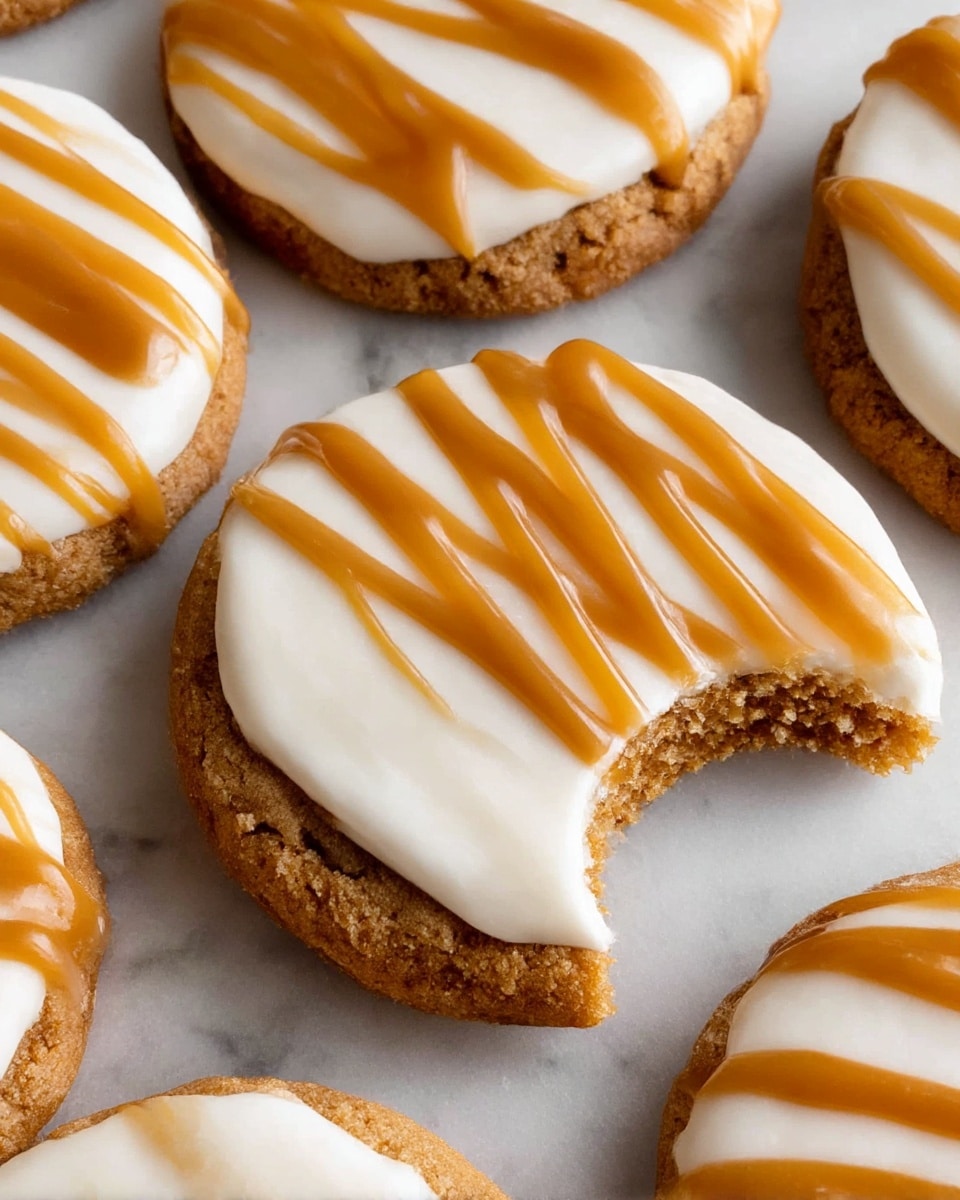 The image shows several round cookies with three visible layers; the bottom layer is a light brown, crumbly cookie base with a rough texture, the middle layer is a smooth, thick white icing, and the top layer is a glossy, caramel-colored drizzle forming wavy lines across each cookie. One cookie in the center has a bite taken out, revealing the crumbly texture of the cookie base under the creamy white icing. The cookies rest on a slightly textured, crinkled parchment paper that contrasts with the cookies. photo taken with an iphone --ar 4:5 --v 7