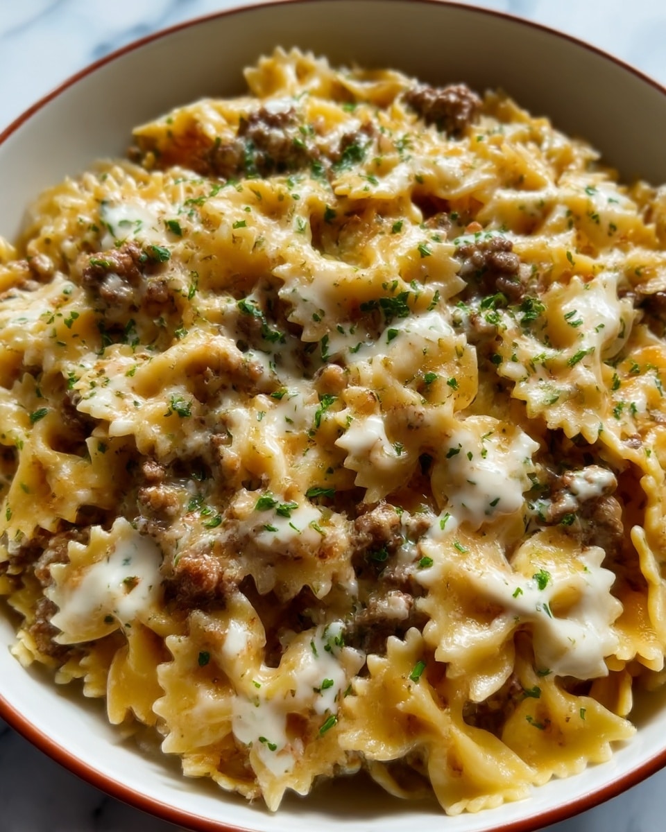 A close-up image of a white bowl filled with three layers of farfalle pasta; the bottom layer is solid light yellow pasta, the middle layer has browned ground beef pieces scattered throughout, and the top layer is covered with melted light golden cheese drizzled slightly with white sauce and sprinkled with green herbs. The bowl sits on a white marbled surface. Photo taken with an iphone --ar 4:5 --v 7