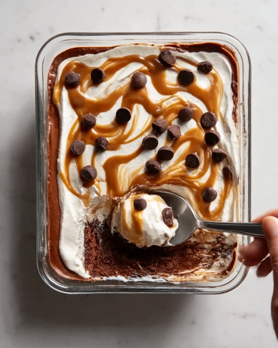 The image shows a square glass dish filled with a layered dessert. The bottom layer is dark brown, smooth and creamy, likely chocolate. On top of this is a thick white creamy layer covering the whole surface. Swirled over the white layer is a caramel-colored sauce creating a wavy pattern. Scattered on top are small round dark chocolate pieces. A spoon is placed inside the dish with some dessert scooped up, and a woman's hand is holding the spoon. The dish sits on a white marbled surface. Photo taken with an iphone --ar 4:5 --v 7